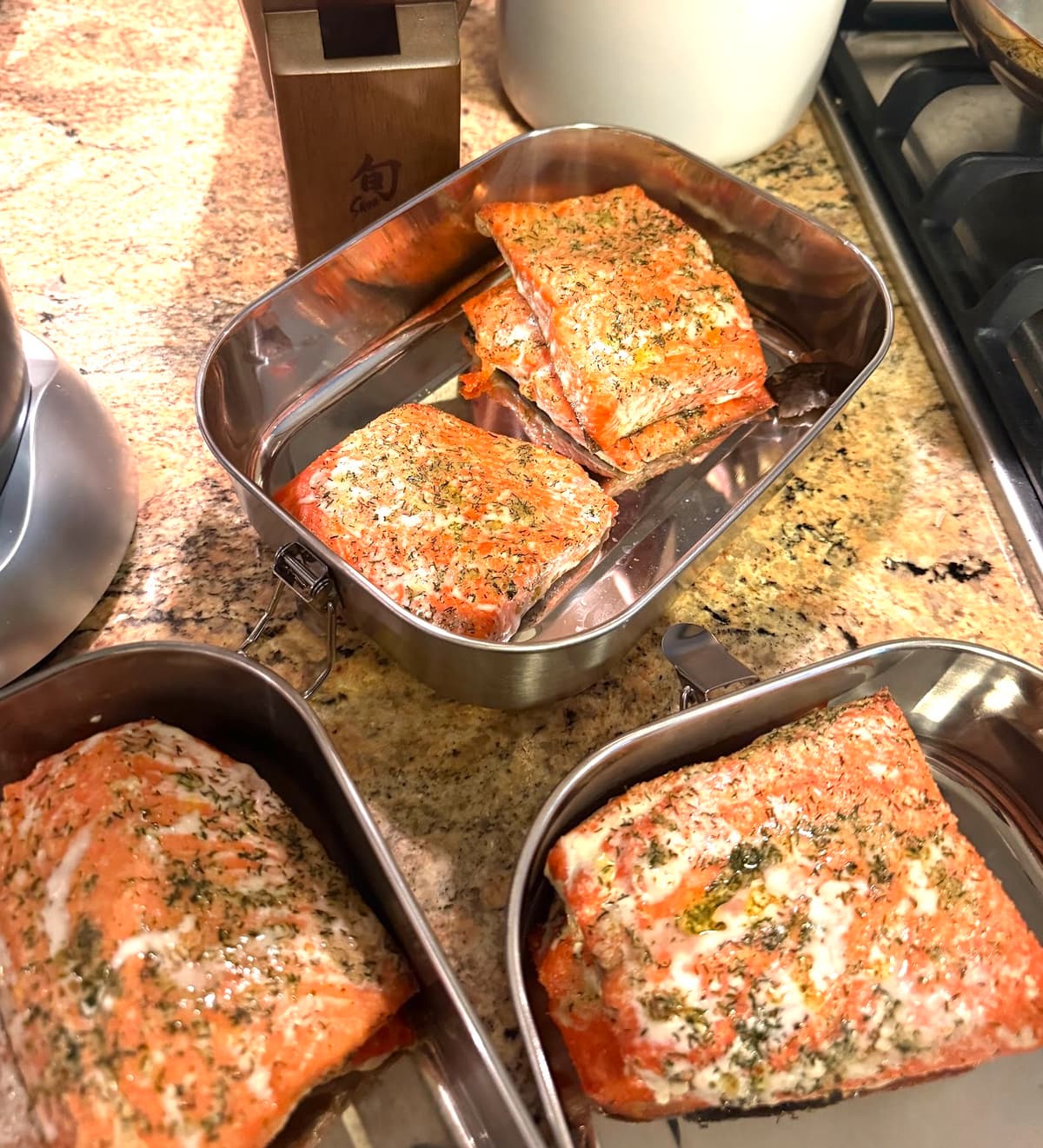 Cooked salmon fillets portioned into stainless steel meal prep containers